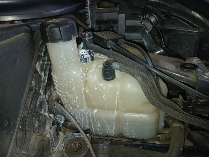 An engine bay with coolant spilled over the reservoir